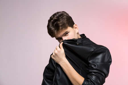 Fashionable Handsome young man in leather jacket posing in the studio against the background of the...