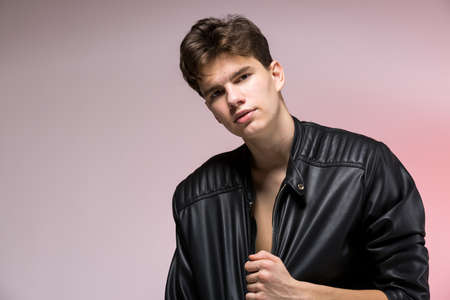 Fashionable Handsome young man in leather jacket posing in the studio against the background of the...