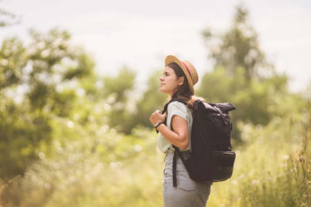 Young travel girl at viewpoint. Hipster girl with backpack. Travel concept. Beautiful woman hiker enjoying amazing landscapes. Holiday vacation and freedom. Back view. Traveler Walking In Nature.の写真素材