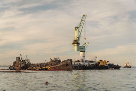 Industrial ship crane lifts old sunken tanker Delfi from Black Sea in Odessa, Ukraine 26 August 2020. Ship crashed near shore sea. Cargo tanker. Ecological disaster oil spill products. Tanker Delphi.のeditorial素材