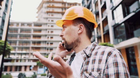 Engineer talking on phone. Architect using phone on construction site. Foreman phone call control...