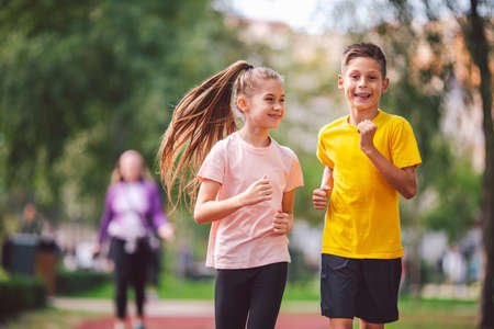 Kids run. Healthy sport. Child sport, heterosexual twins running on track, fitness. Joint training. Running training outdoor brother and sister pre-teen. Jogging with friend. Children athletes.の写真素材