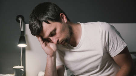 Young man ill with flu at home. Guy having flu. Diseased male sitting on bad. Sick man monitor body temperature with thermometer. Body temperature measurement. Have i got the fever.の写真素材