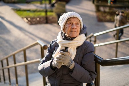 Portrait of happy senior caucasian woman with cup of coffee to go in winter clothes, white knitted...