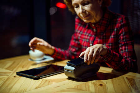 Contactless payment. Nfs payment by phone. Client of cafe or restaurant holding smartphone over...