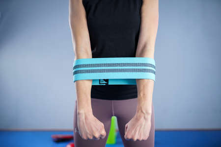 Athletic woman in sportswear barefoot using thick elastic fabric workout bands for stretch fitness...
