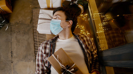 Depressed man, isolation at home, quarantine pandemic on Christmas. Pessimistic guy feels trapped in house decorated New Years decor on period isolation. Emotional breakdown.の写真素材