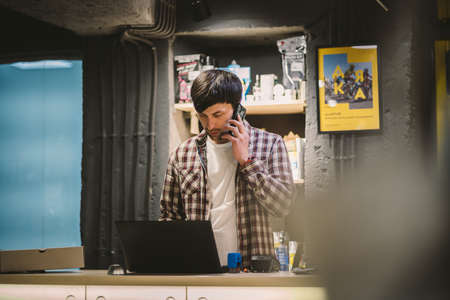 Small business owner on phone and computer in store. Sport shop worker making call with cell phone. Salesman working and talking on cell phone in bicycle shop. Seller taking orders by phone.の写真素材