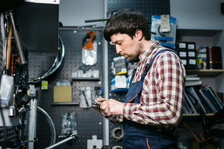 Bike shop mechanic fixing bicycle wheel in workshop. Serviceman repair, maintenance cycle. Velocipede repairing bicycle in bike shop. Bicycle repair service concept. Environmentally friendly vehicles.の写真素材