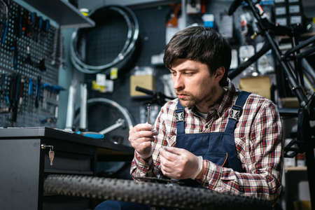 Bicycle mechanic fixing cycle wheel in repair shop. Velocipede service. Repairer male bike shop...