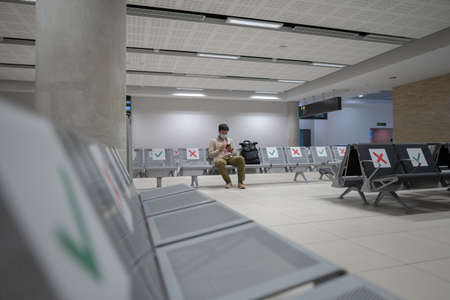 Man wearing protective mask upset by cancellation flight, writes message to his family, sitting in empty terminal at airport of Cyprus, Paphos city, due to pandemicの写真素材