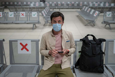 Man wearing protective mask upset by cancellation flight, writes message to his family, sitting in empty terminal at airport of Cyprus, Paphos city, due to pandemicの写真素材