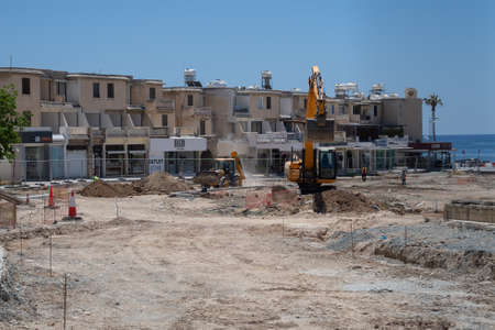 May 11, 2021 Cyprus, Paphos. Heavy machinery and construction equipment are working on renovation of pavement near harbor in downtown Paphos. Road repair concept. Backhoe loader on construction siteのeditorial素材