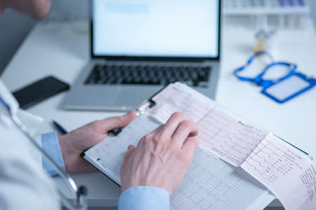 Cardiologist reading an ECG print-out. Doctor analyzing electrocardiogram. Practitioner examine...
