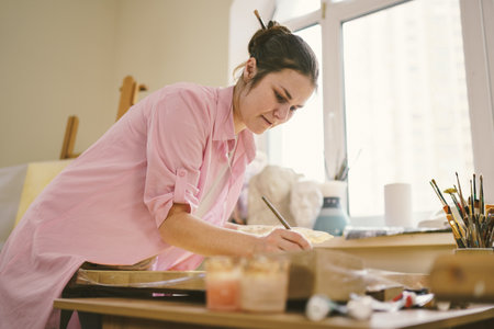 Art, creativity, hobby and creative occupation concept. Bringing creativity to life. Woman painting in art studio. Attractive female artist painting in workshop. Woman hobby, activity, profession.の写真素材