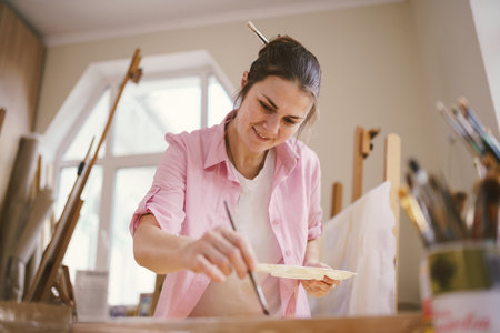 Art, creativity, hobby and creative occupation concept. Bringing creativity to life. Woman painting in art studio. Attractive female artist painting in workshop. Woman hobby, activity, profession.の写真素材