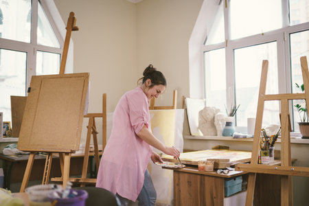 Art, creativity, hobby and creative occupation concept. Bringing creativity to life. Woman painting in art studio. Attractive female artist painting in workshop. Woman hobby, activity, profession.の写真素材