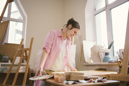 Art, creativity, hobby and creative occupation concept. Bringing creativity to life. Woman painting in art studio. Attractive female artist painting in workshop. Woman hobby, activity, profession.の写真素材