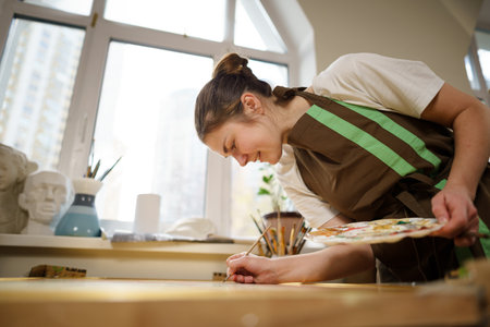 Female artist working in studio. Creative workspace, painting class, easel with canvas, art therapy. Inspiration, creativity, talent, craft concept. Artist studio interior. People, leisure and hobby.の写真素材
