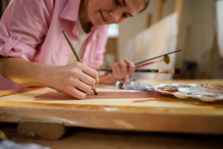 Female artist working in studio. Creative workspace, painting class, easel with canvas, art therapy. Inspiration, creativity, talent, craft concept. Artist studio interior. People, leisure and hobby.の写真素材