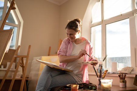 Female artist working in studio. Creative workspace, painting class, easel with canvas, art therapy. Inspiration, creativity, talent, craft concept. Artist studio interior. People, leisure and hobby.の写真素材
