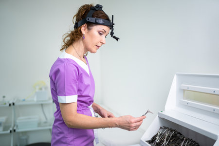 Profession medical industry. Portrait of woman ENT doctor posing in office before examining patient. Physician in bright colored uniform with medical equipment and tools for ENT practice in hospital.の写真素材