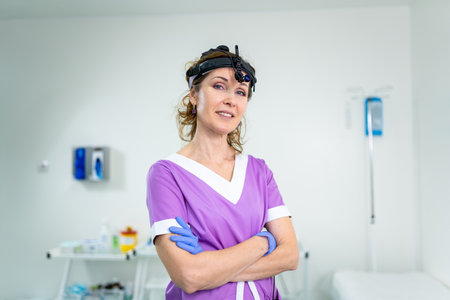 Profession medical industry. Portrait of woman ENT doctor posing in office before examining patient. Physician in bright colored uniform with medical equipment and tools for ENT practice in hospital.の写真素材