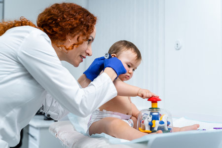 Pediatrician doctor concept. Children medical care. One year old baby girl examined by female pediatrician in clinic office. Child visiting doctor for health check-up. Doctor examine little patient.の写真素材