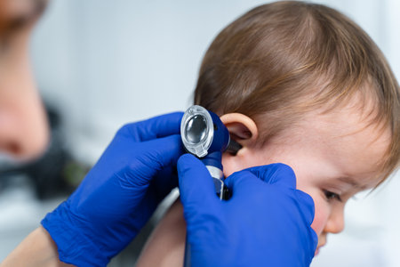 Red-haired female doctor examines little child for less than a year in a modern clinic. Pediatrician during examination baby in the hospital. Childrens healthcare. Diagnostics and treatment for kid.の写真素材