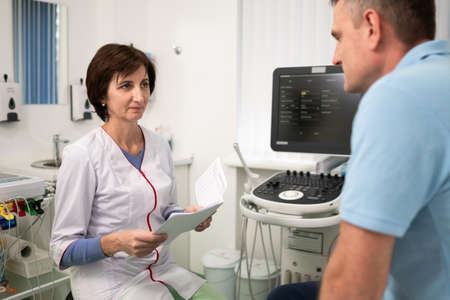 Doctor cardiologist in the office of ultrasound diagnostics with the patient examines medical tests...