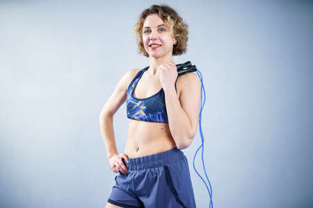 Smiling sportswoman posing with a skipping rope. Female with muscular body posing with jump rope. Fitness model. Body positivity, sport, fitness concept. Healthy lifestyle. Fit woman with jump rope.の写真素材