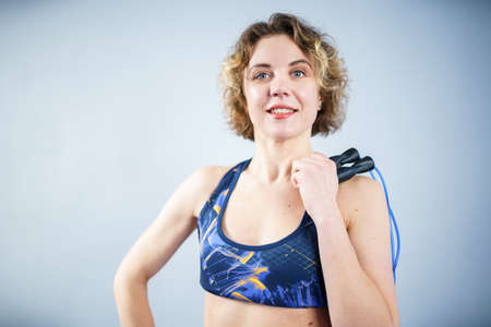 Smiling sportswoman posing with a skipping rope. Female with muscular body posing with jump rope. Fitness model. Body positivity, sport, fitness concept. Healthy lifestyle. Fit woman with jump rope.の写真素材
