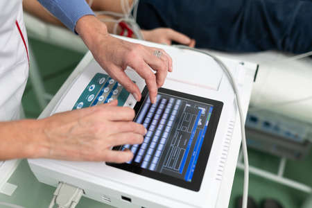 Medical equipment for electrocardiogram. Doctors doing ECG test on male patient. Diagnostic heart disease heart attack, tachycardia. Electrocardiography procedure. Cardiologist doing check-up test.の写真素材