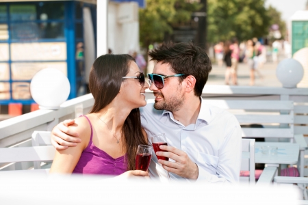 young happy couple drinking red wine in cafeの写真素材