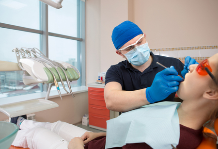 young doctor dentist examines the mouth of the patientの写真素材