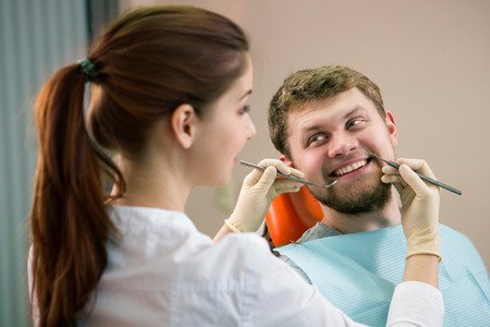 young doctor dentist examines the mouth of the patientの写真素材