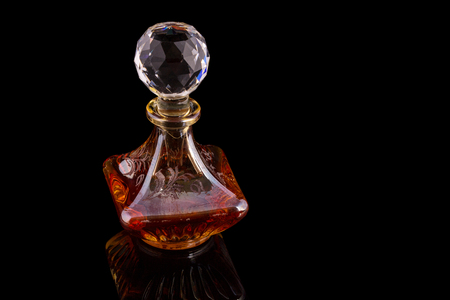 Close Up Shot Of Traditional Luxury Arabic Oud Red Oil Perfume In A Beautiful Handmade Clear Crystal Glass Jar Bottle and Glass Dropper Isolated On Black Background Antique Style, Text Spaceの写真素材