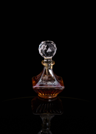 Close Up Shot Of Traditional Luxury Arabic Oud Oil Perfume In A Beautiful Handmade Clear Crystal Glass Jar Bottle and Glass Dropper Isolated On Black Background Antique Style, Text Spaceの写真素材