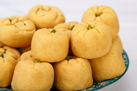 Round shaped Chickpea cookie pastries made of gram flour and Pistachio traditional Iranian Sweets: Nokhodchi close up shot in a turquoise plateの写真素材