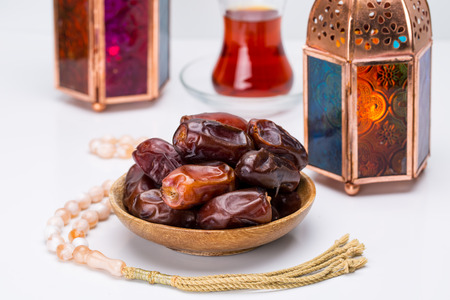 Ramadan Kareem Festive, close up of dates on wooden plate and rosary with oriental Lantern lamps and...