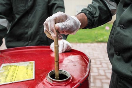 Close Up Hands Of Men At Work Holding The  Measurement Tool Dipstick And Measuring The Oil Level...