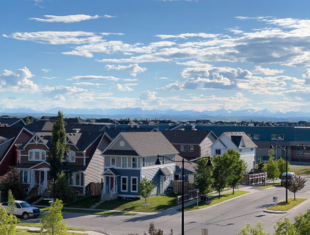 A quiet suburban street lined with elegant homes, bathed in cool tones.The distant mountains under a sky filled with textured clouds add depth and a sense of freshness to the sceneの写真素材
