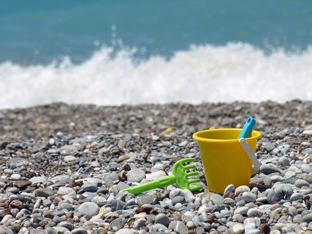 Yellow bucket and green rake on a beach.の写真素材