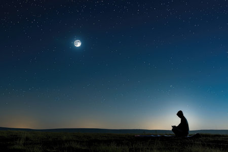 A lone figure in prayer beneath the moonlit Ramadan skyの素材