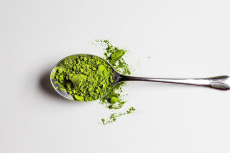 A spoonful of vibrant matcha powder on a white backgroundの素材