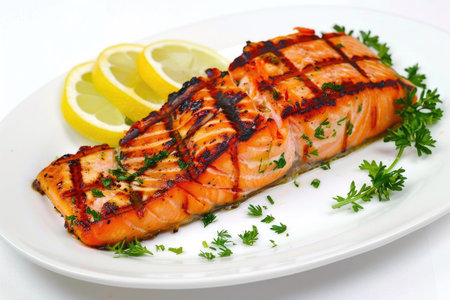 A succulent grilled salmon fillet served on a white plate against a clean white backgroundの素材