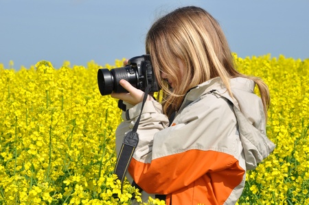 girl taking photos in rapeseed field の写真素材