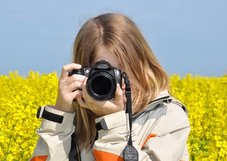 girl taking photos in rapeseed field の写真素材