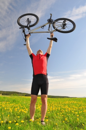 biker with the mountain bike in the dandelion fieldの写真素材