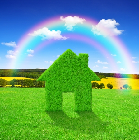 Green grass house symbol with rainbow on meadow の写真素材